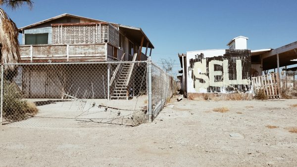 abandoned buildings in saltonsea with graffiti that says "sell"