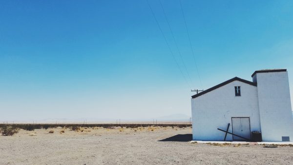 white church in the desert with a fallen cross over the door