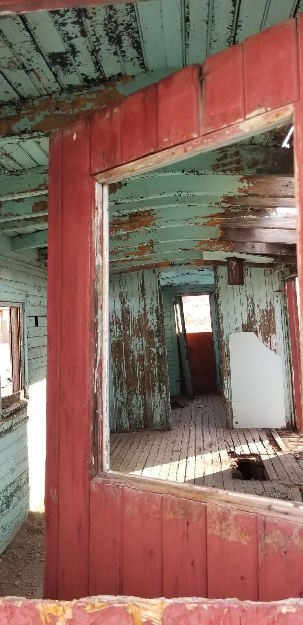 looking through a red door inside a green dilapidated house