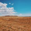 junction sign next to barbed wire fence and brown landscape