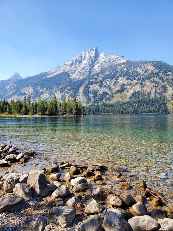 photo of clear water with pebbles at the bottom and mountain in background