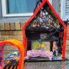 paper mache art house that is neon orange has faces in the attic and living room on the ground floor