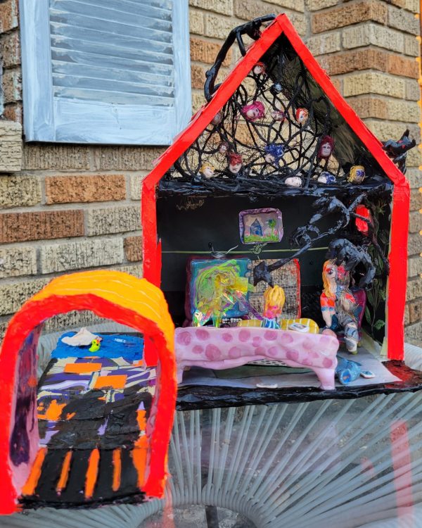 paper mache art house that is neon orange has faces in the attic and living room on the ground floor